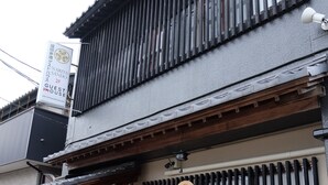A traditional Japanese building with a wooden entrance, a bench outside, and a sign indicating it is a guest house.