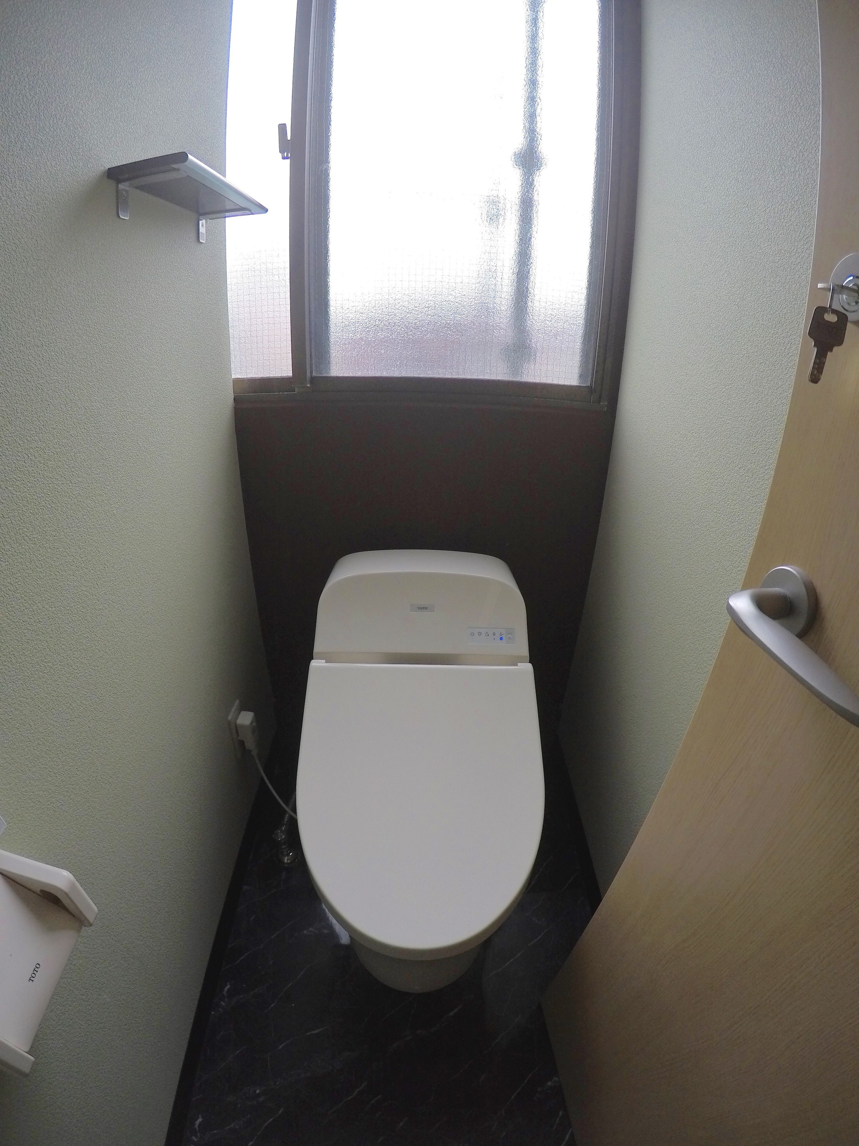 Un baño pequeño con inodoro, ventana y zona de ducha.