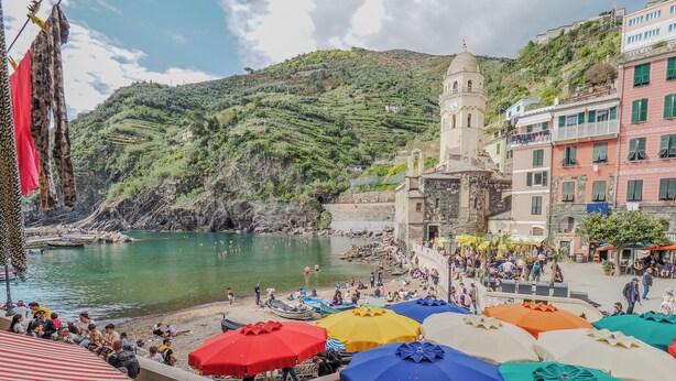 Ein Küstenort mit Strand, einer Kirche und bunten Sonnenschirmen.