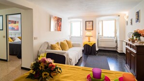 Ein Hotelzimmer mit einem Bett, einem Sofa, einem Esstisch mit gelber Tischdecke und einer kleinen Küchenzeile.