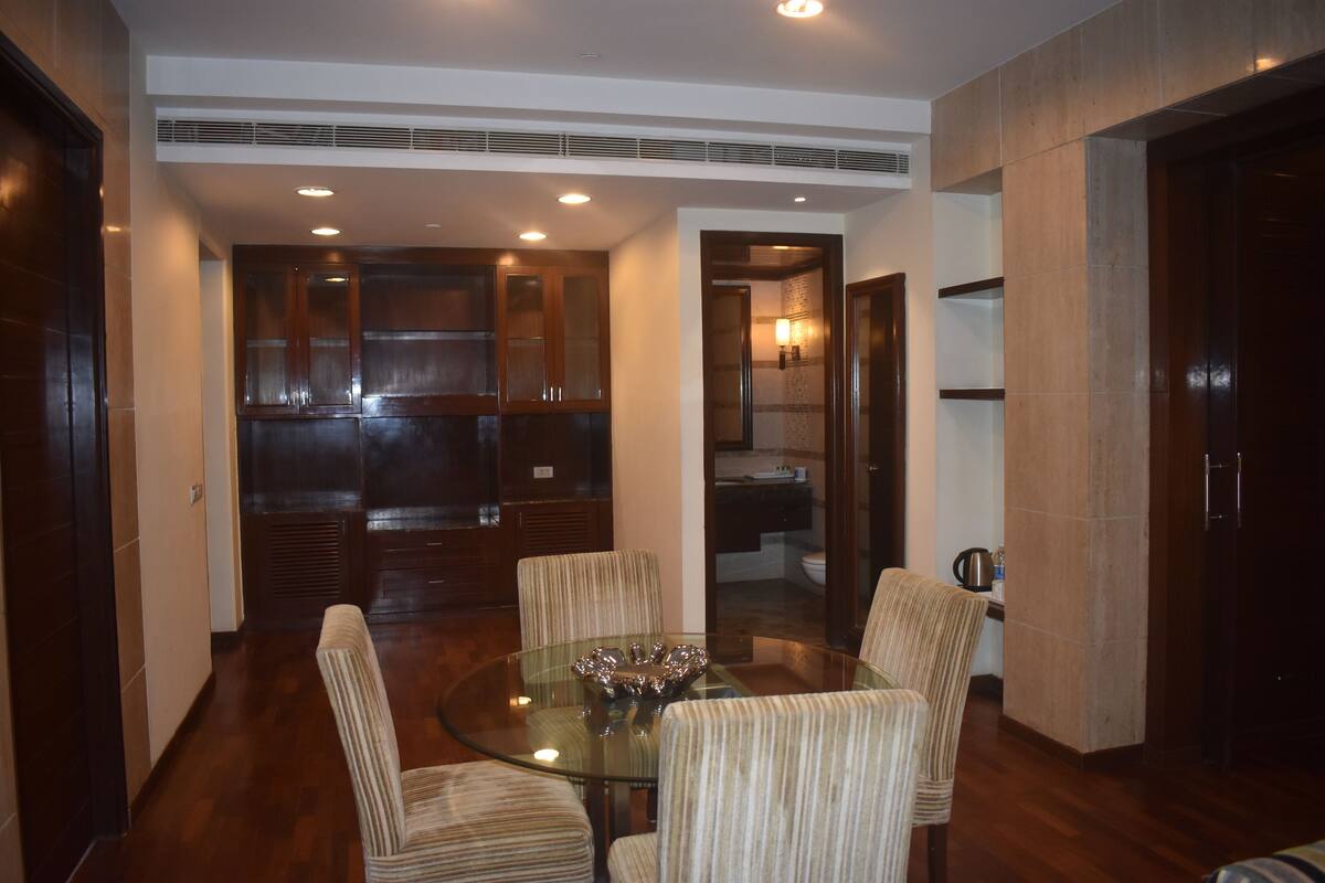 A modern kitchen with dark wood cabinets, a glass dining table, and striped chairs.