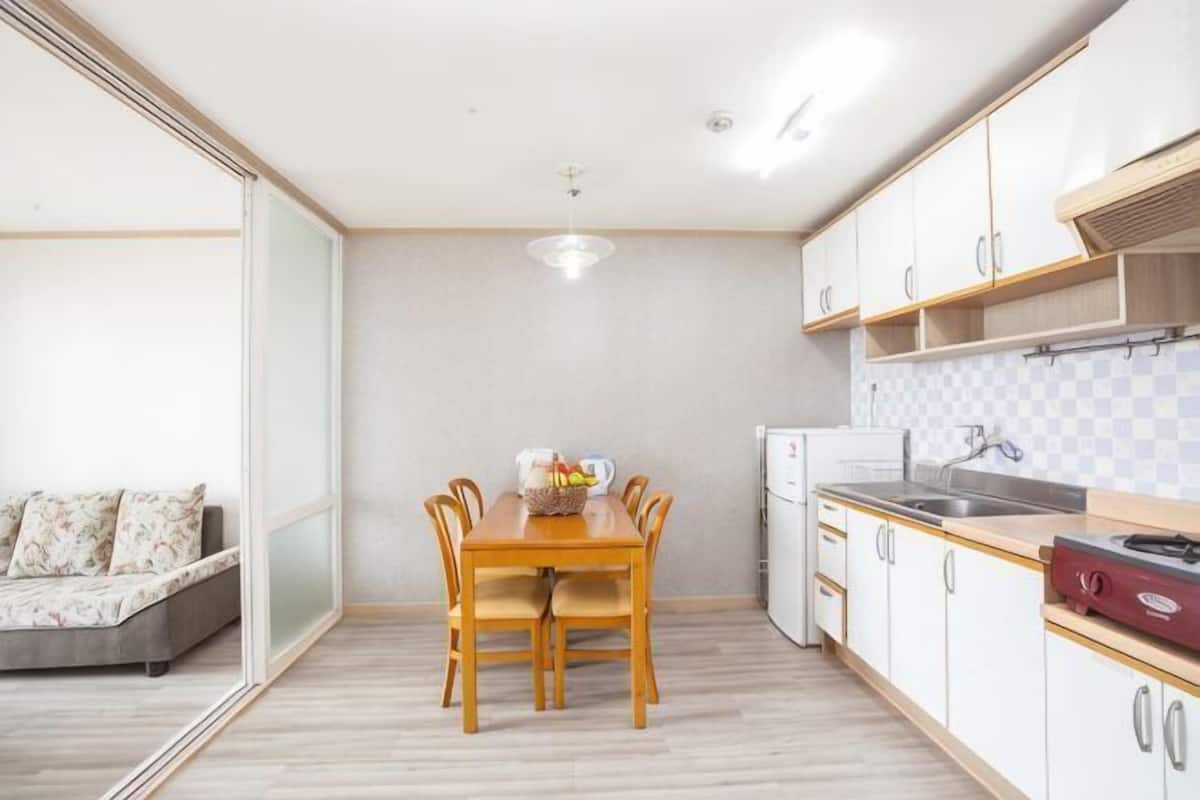 Une cuisine de taille réduite comprenant une table à manger, un réfrigérateur et un évier.