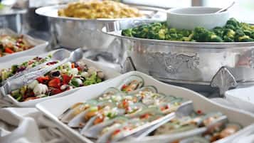 A buffet with various dishes, including a large bowl of broccoli, a salad, and other assorted foods.