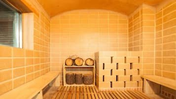 A sauna with tiled walls, wooden benches, and a shelf with logs.