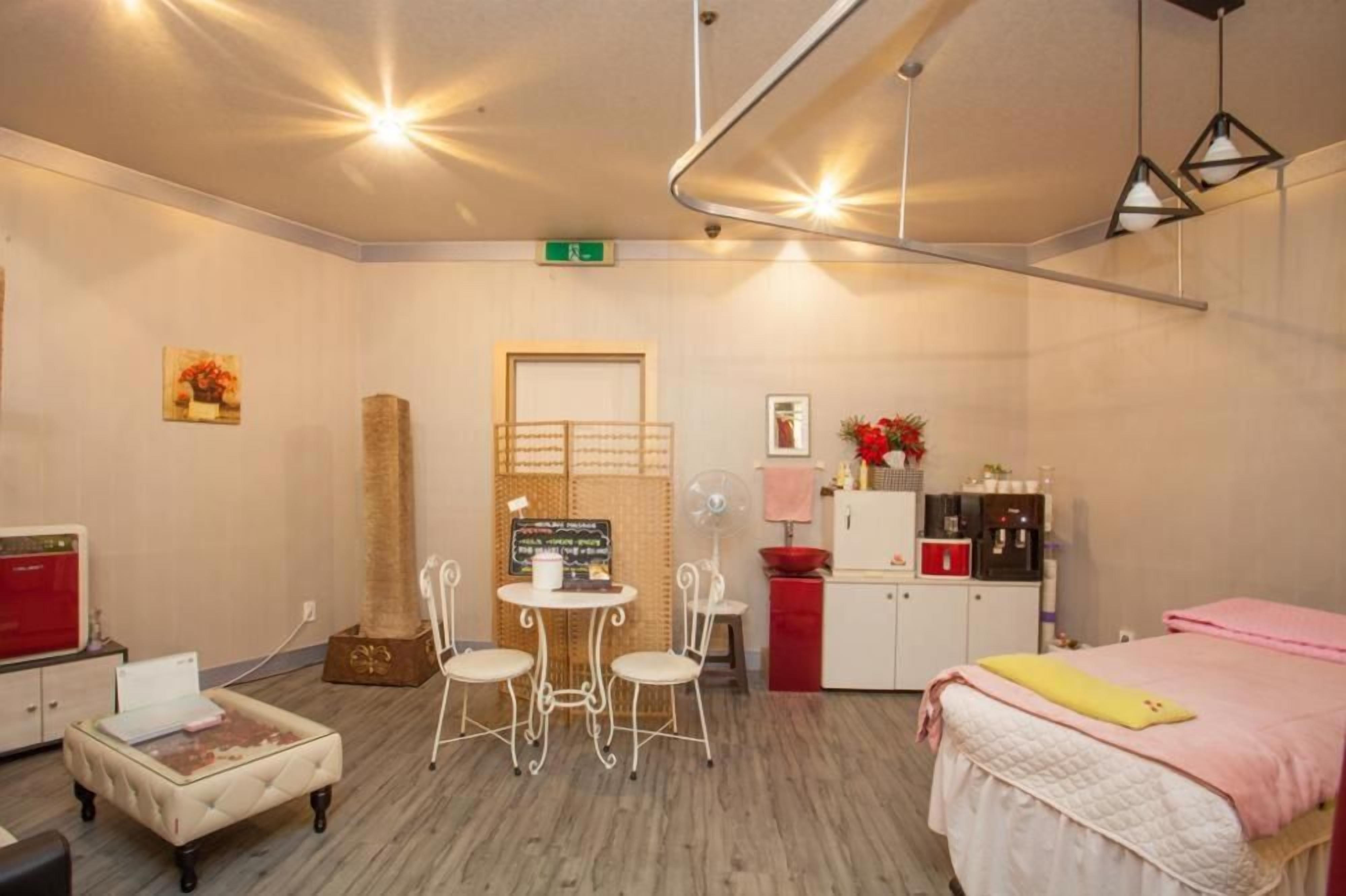 Habitación de hotel con cama, una pequeña mesa con sillas, kitchenette y una zona de estar con ventilador.