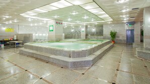 Una amplia piscina cubierta con varias pistas de natación, rodeada de muros de piedra y suelo de baldosas.
