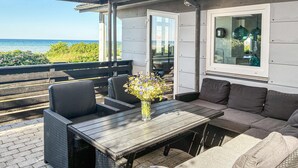 Eine Terrasse mit Korbmöbeln, einem Tisch und einem Blumenstrauß.