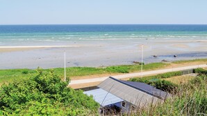 Blick auf die Küste mit Strand, einem Pfad und einem Gebäude mit Metallbedachung.