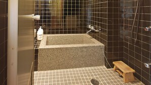 A bathroom with a rectangular granite sink, a small wooden bench, and a tiled floor. - Nakamasu Ryokan (Takeo)