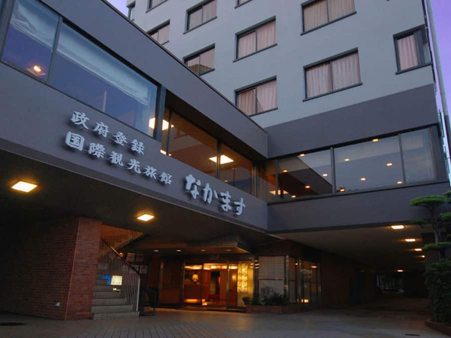 A multi-story hotel with a modern design, featuring a prominent entrance with glass doors and a sign in a foreign language.
