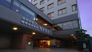 Un hotel moderno a più piani, con un ingresso ben visibile caratterizzato da porte in vetro e una insegna in lingua straniera.