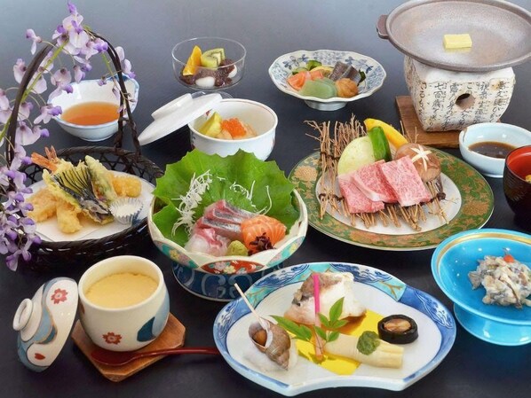 Verschiedene japanische Gerichte, darunter Sushi, Sashimi und Tempura, serviert auf traditionellen Keramiktellern und -schalen.