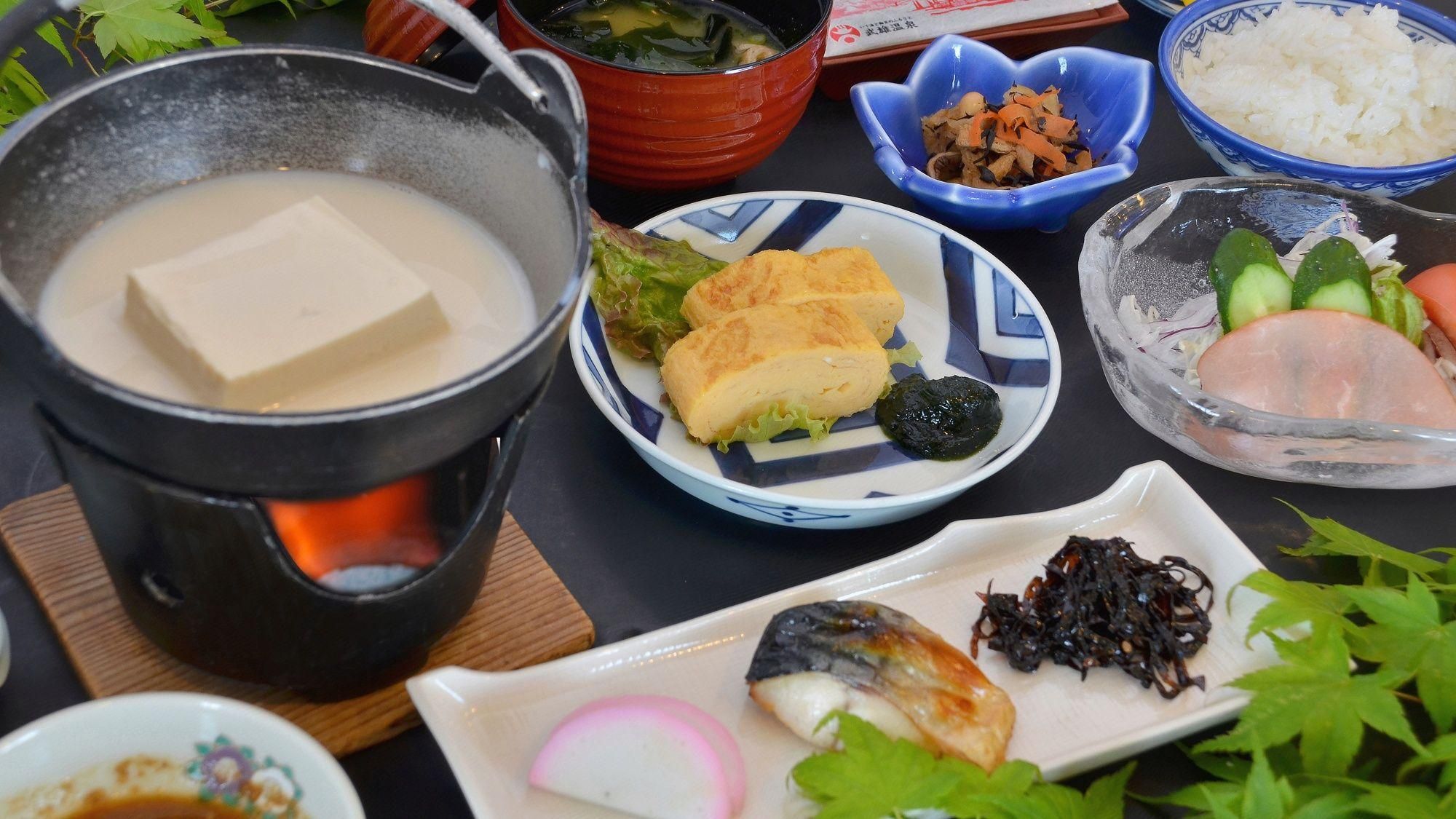 Diversos pratos, incluindo tofu, vegetais e peixe, servidos em uma mesa com uma panela de sopa.