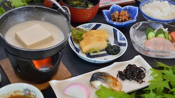 Variedad de platos, incluyendo tofu, verduras y pescado, servidos en una mesa con una olla de sopa.
