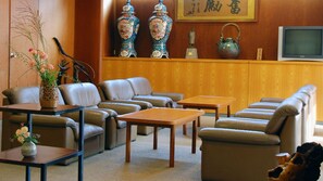 Un salón de estilo japonés tradicional con un conjunto de sofás, una mesa y objetos decorativos como jarrones y una tetera.