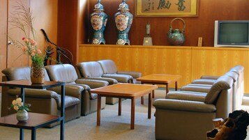 Un salón de estilo japonés tradicional con un conjunto de sofás, una mesa y objetos decorativos como jarrones y una tetera.