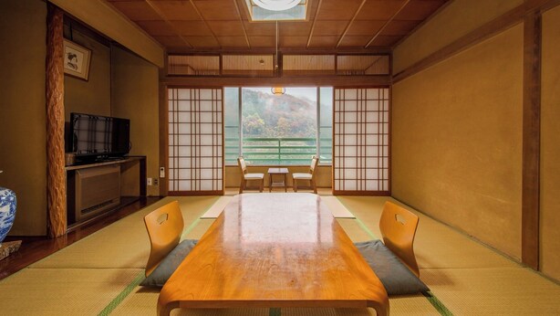 A traditional Japanese room with tatami flooring, a low table, and sliding doors. - Konishi Ryokan (Miyoshi)