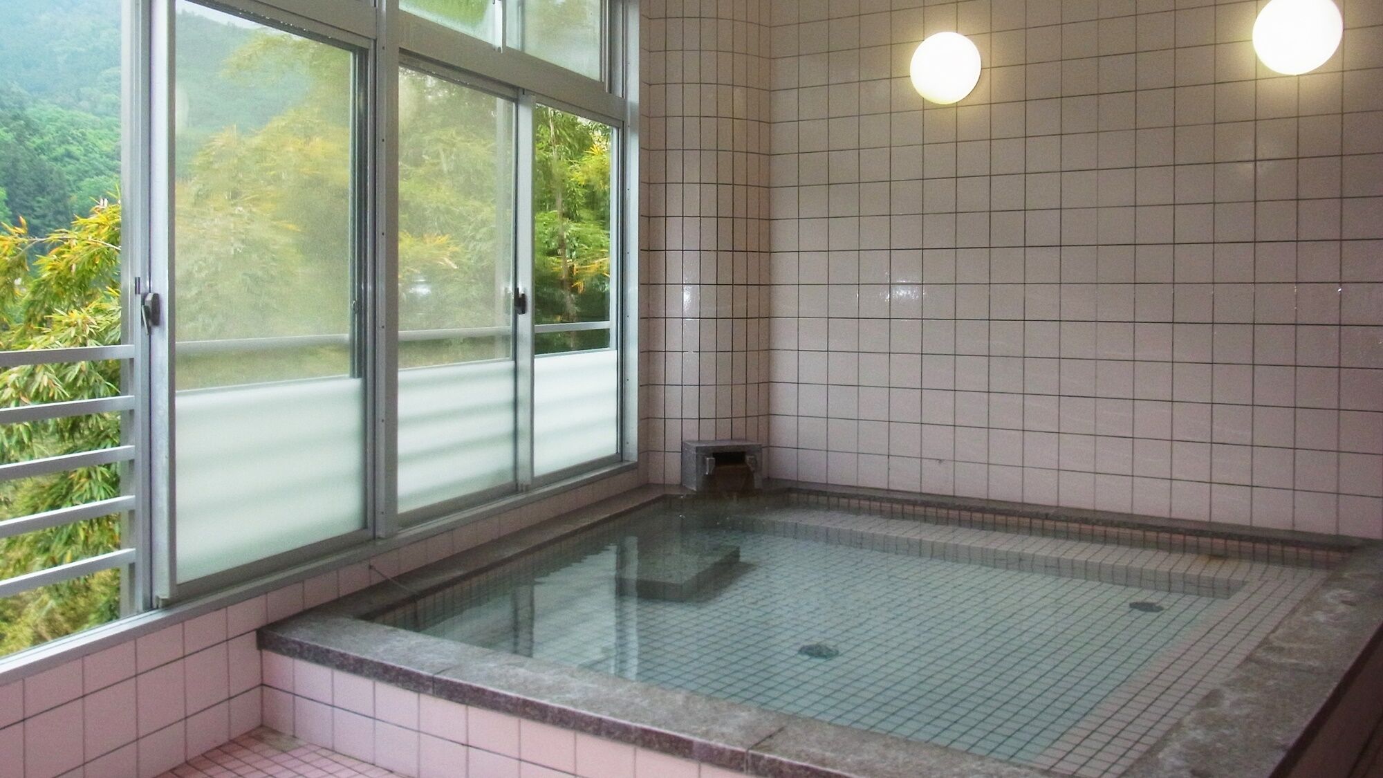 A room with a glass-enclosed window, tiled walls, and a tiled floor.