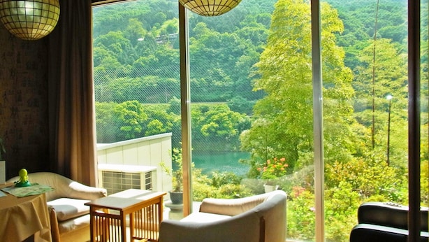 Quarto com uma grande janela que oferece vista para uma paisagem verde exuberante.