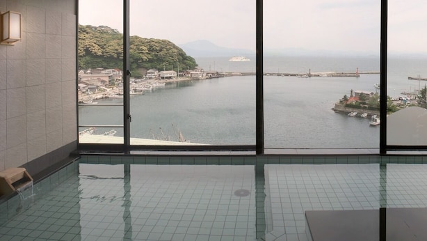 Une vue depuis un balcon, avec une grande fenêtre donnant sur une marina et une île lointaine.