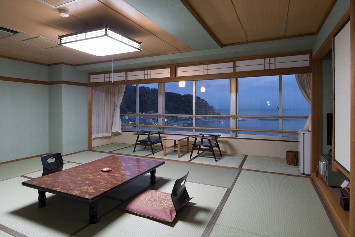 Ein traditioneller Tatami-Raum mit niedrigem Tisch, Stühlen und Meerblick.