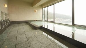 Une piscine intérieure moderne, dotée d’une paroi en verre, d’un espace sauna et offrant une vue sur un paysage enneigé grâce à de grandes fenêtres.