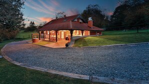 Een huis met een overdekte patio, een schoorsteen en een grindpad.