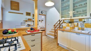 Een moderne keuken met houten kastjes, een gasfornuis en een eethoek met een tafel gedekt voor twee personen.