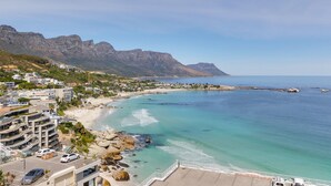 A coastal town with a beach, rocky shoreline, and mountains in the background. - Dunmore Views (Cape Town)