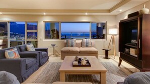 A modern living room with a large window, a sofa set, a coffee table, and a TV stand. - Dunmore Views (Cape Town)