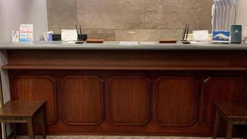 A reception desk with a wooden panel design, a counter with various items, and a tiled wall behind.