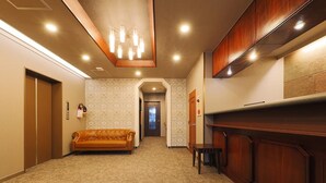 Un pasillo de hotel con un sofá, paneles de madera y una puerta al final.