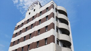 Un hotel de varios pisos con un diseño arquitectónico distintivo, que presenta un balcón curvo a la derecha y un cielo despejado al fondo.