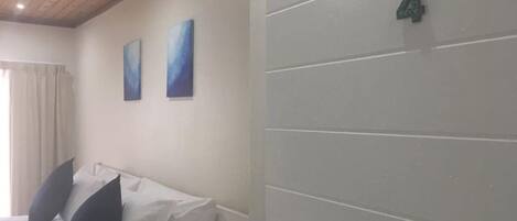 A hotel room with a bed, two pillows, a nightstand, a lamp, and a door with the number 4.