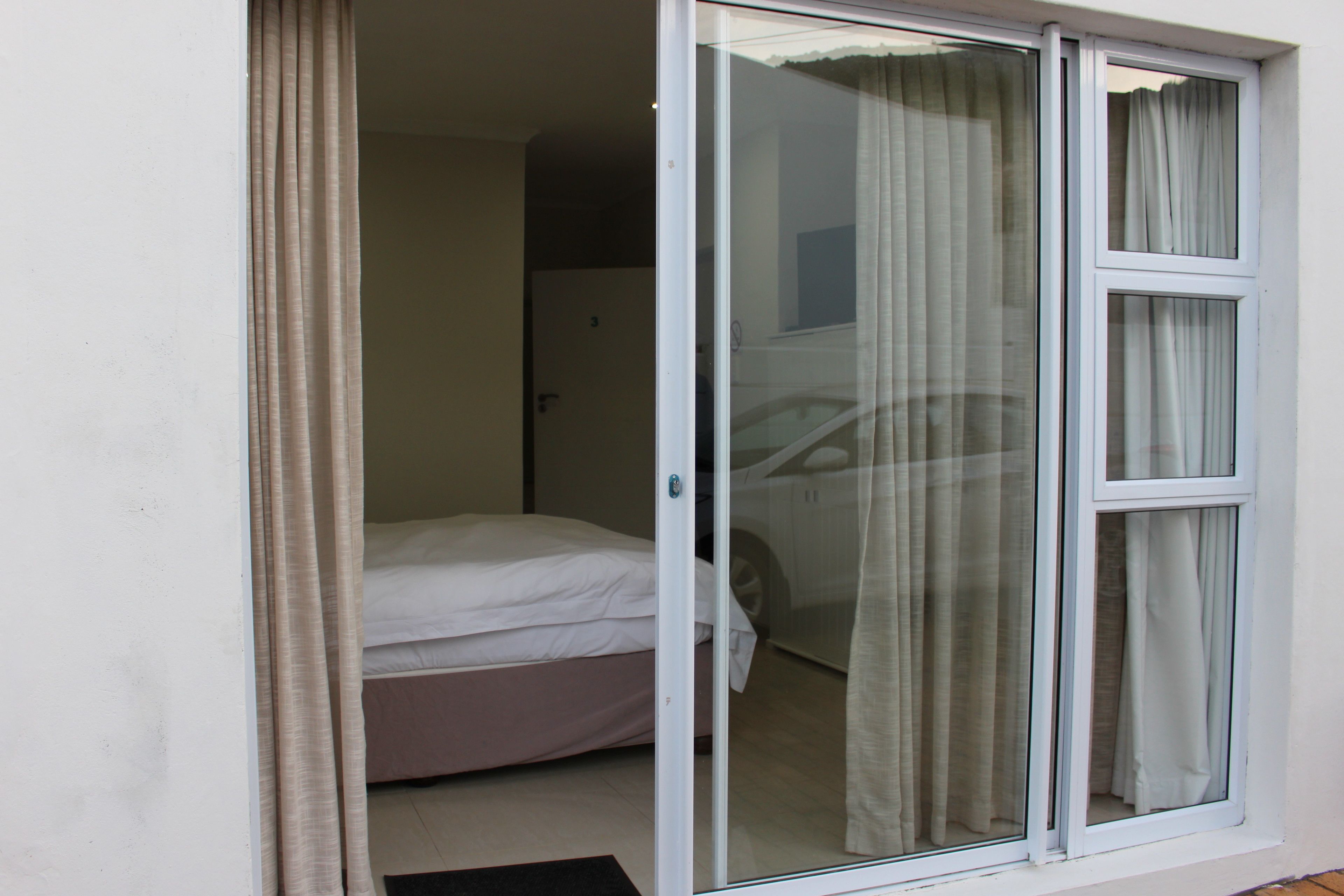 Une chambre avec un lit, une porte-fenêtre coulissante et une vue sur une voiture à travers la fenêtre.