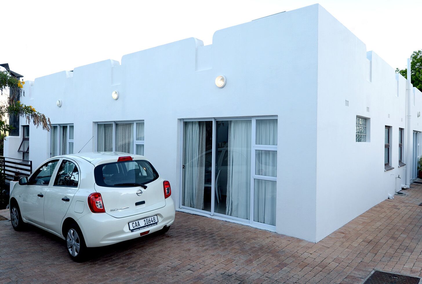 A white building with a car parked in front.