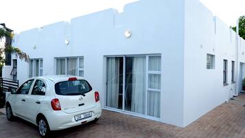 A white building with a car parked in front.