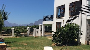 A swimming pool with two lounge chairs, a white building with a staircase, and a view of mountains in the background. - Paarl Mountain Lodge (Paarl)