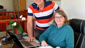 A man and a woman sitting at a desk with a laptop, surrounded by papers and a payment terminal. - Paarl Mountain Lodge (Paarl)