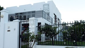 A white building with a reception sign, a gate, and a number '21' on the wall. - Paarl Mountain Lodge (Paarl)
