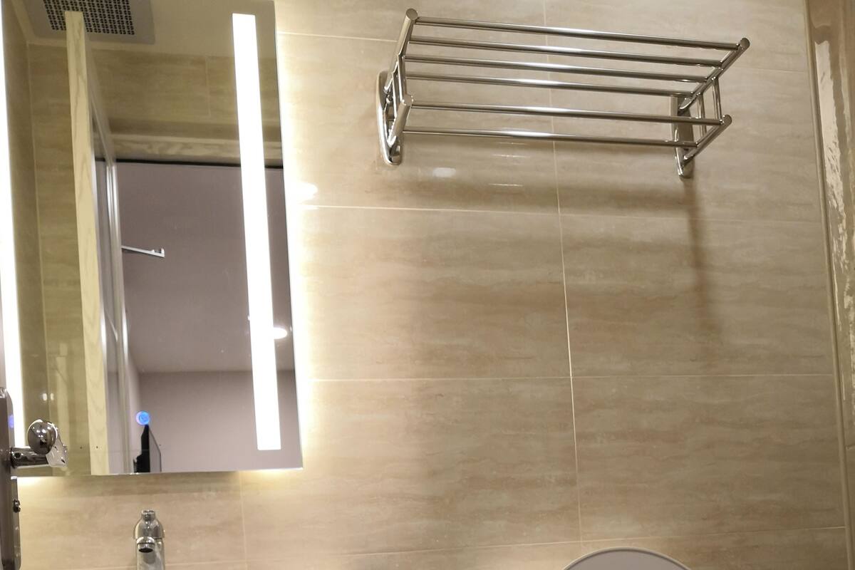 A bathroom with a toilet, a sink with a mirror, and a towel rack.