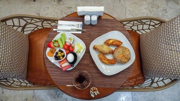 A dining table with plates of food, condiments, and a cup of coffee.