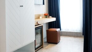 Une chambre moderne avec une grande armoire, une table de chevet, un miroir et une fenêtre avec des rideaux.
