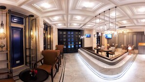 Un hall d’hôtel doté d’un comptoir d’accueil incurvé, d’un espace salon et d’un écran de télévision.