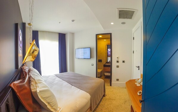 A hotel room with a bed, a desk, a television, and a bathroom visible through an open door. - Atik Pera Hotel (Istanbul)