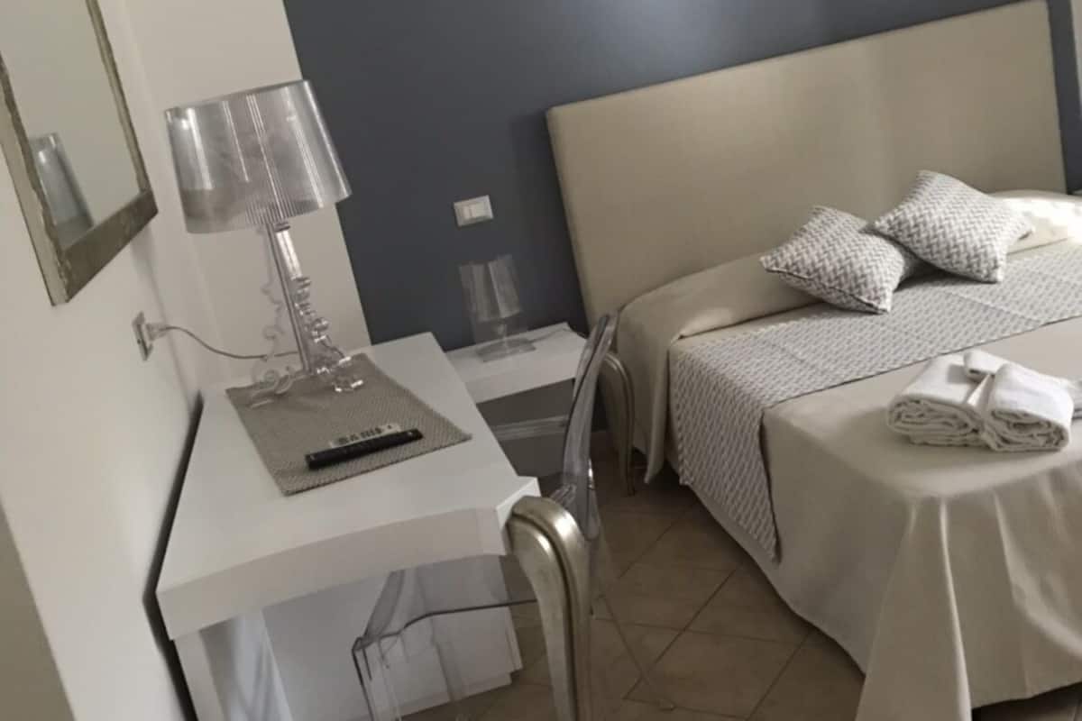 Ein Hotelzimmer mit einem Bett, einem Schreibtisch mit Lampe und einem Stuhl.