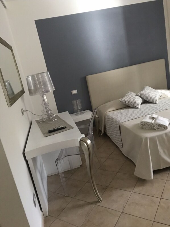 Una habitación de hotel con una cama, un escritorio con lámpara y una silla.