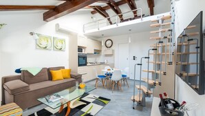 Un salon moderne avec une table basse en verre, un canapé et un coin repas avec des chaises.