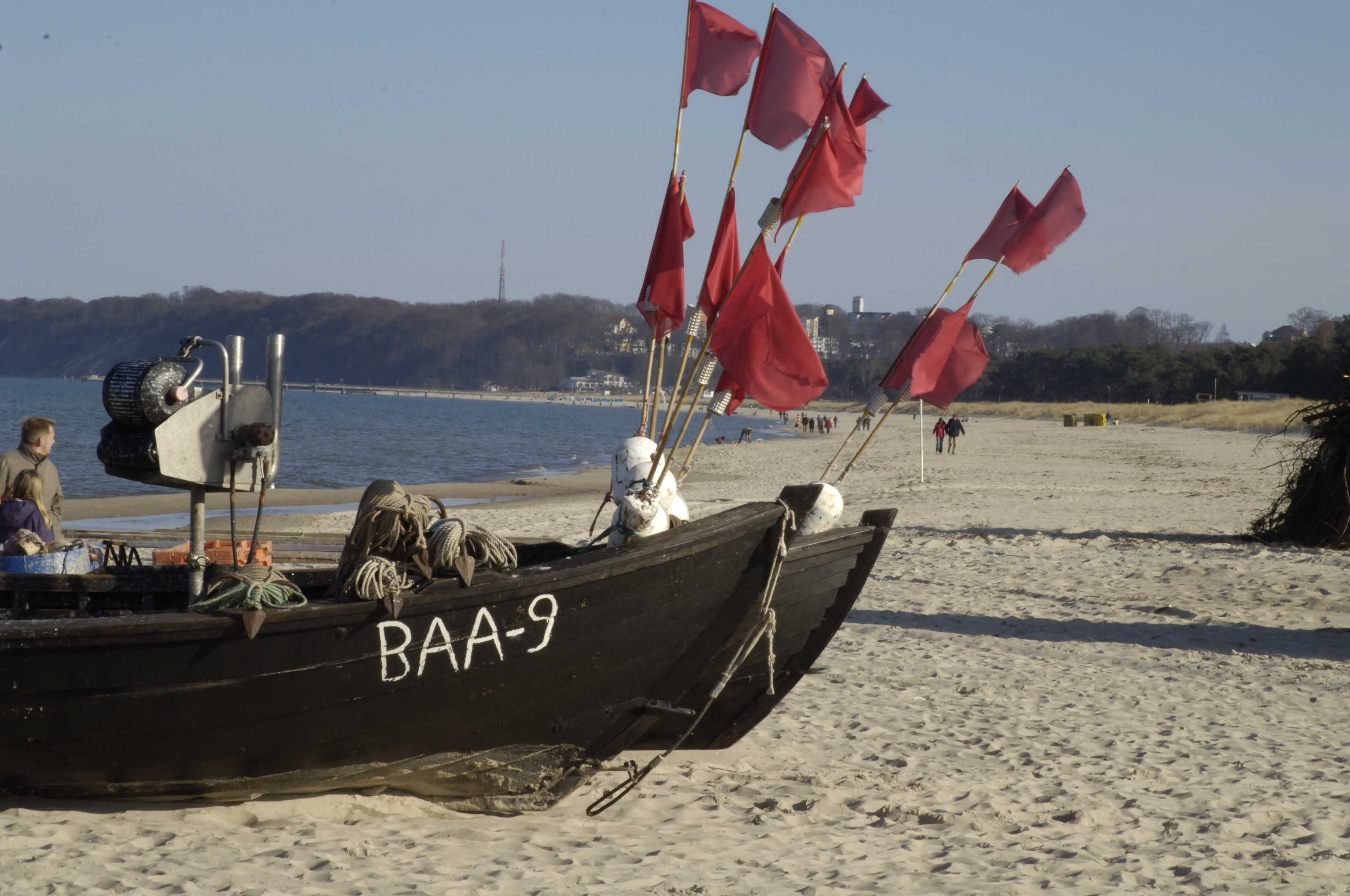 En båt med identifieringsnummer BAA-9 ligger på en sandstrand.