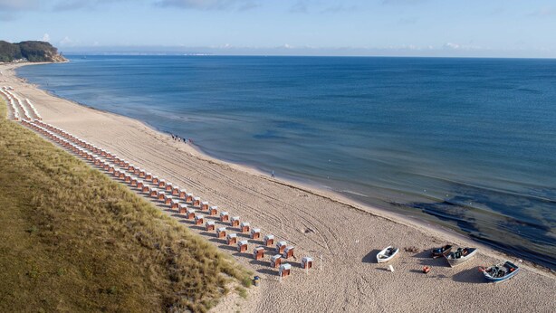 Una playa con hileras de cabañas y barcos.
